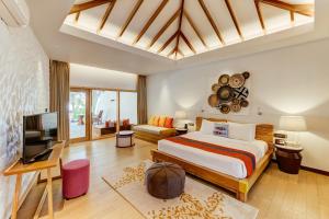 a bedroom with a large bed and a television at Cinnamon Dhonveli Maldives - Complimentary Speedboat Return for 2 pax on 7 nights or more stays valid to 31 Oct 2027 & up to 2 kids stay free in North Male Atoll