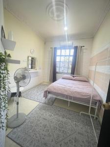 a bedroom with a bed with a fan and a window at Tokbah Homestay Alor Setar in Alor Setar