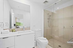 uma casa de banho branca com um chuveiro e um WC. em Modern 1BR in the Heart of South Brisbane w Wifi Parking em Brisbane