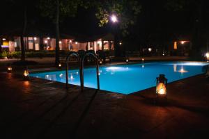uma piscina iluminada à noite com luzes em Tiger Trails Resort em Tāla