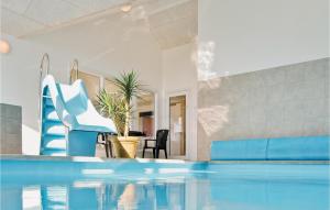 ノーポにあるBeautiful Home In Nordborg With Sauna, Private Swimming Pool And Indoor Swimming Poolのスイミングプール(青い椅子、テーブル付)