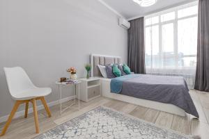 a white bedroom with a bed and a chair at Apart Astana, Комплекс Парасат 226, рядом с ботаническим садом, Барыс арена, Астана арена in Astana
