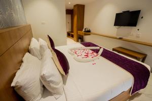 a bedroom with a bed with pillows and a tv at HOTEL VARDHA Inn in Bhavāni