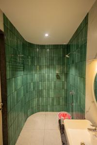 a green tiled bathroom with a sink and a shower at HOTEL VARDHA Inn in Bhavāni