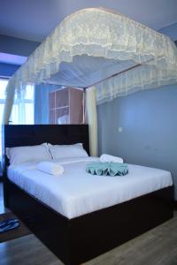 a bedroom with a canopy bed with white sheets at BRIMAK HOTEL in Embakasi