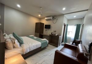 een slaapkamer met een bed en een bank erin bij D Royal Palm in Jorhat
