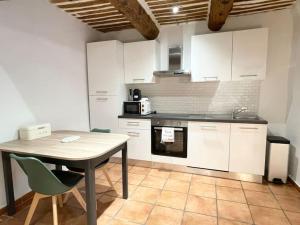 une cuisine avec des armoires blanches et une table et des chaises dans l'établissement Studio 40m2 au cœur du village, à Cornillon-Confoux 8 autres photos