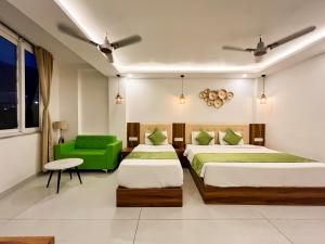 a hotel room with two beds and a green chair at Wanna Stay Rishikesh in Rishīkesh
