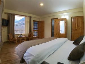 a bedroom with a large bed and two windows at Cloud 9 Chalet in Manāli