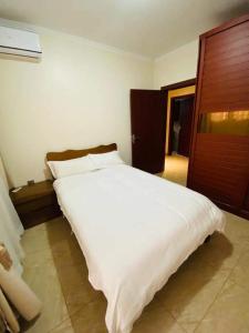 a bedroom with a large white bed with a wooden door at Marangu (3bedroom) in Lusaka