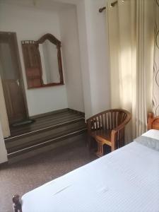 ein Schlafzimmer mit einem Bett, einem Spiegel und einem Stuhl in der Unterkunft Lavista Holiday Bungalow in Wellawaya