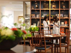 Due donne in piedi a un tavolo in una biblioteca di La Jolie Motomachi a Hakodate