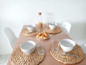 a table with plates and cups and bread on it at Studio l'Oasis - Piscine, plage de La Baule 10 min in Guérande