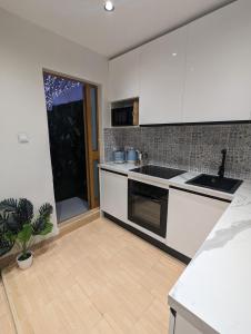 a kitchen with white cabinets and a potted plant at Modern & Cosy 1 Bed Maisonette - Close to Salina Bay in St. Paul's Bay