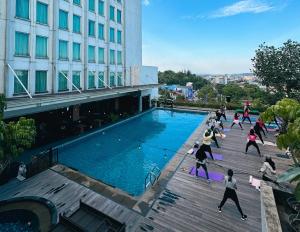 a group of people exercising by a swimming pool at Five Premiere Hotel in Samarinda