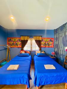 two beds in a room with blue walls at Elephant bungalow at Ya Nui beach in Phuket