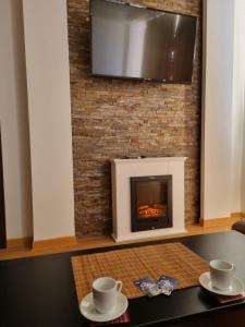 a fireplace with a television on a brick wall at Apartman KUTIJA Kopaonik in Kopaonik