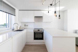 eine weiße Küche mit weißen Schränken und einem Waschbecken in der Unterkunft Belgravia Apartment 45 in London