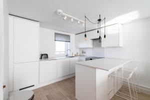 eine weiße Küche mit weißen Schränken und einer Theke in der Unterkunft Belgravia Apartment 45 in London