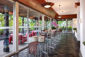 a restaurant with tables and chairs and windows at Lumire Hotel & Convention Centre in Jakarta