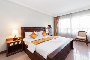 a woman standing in a bedroom with a large bed at Monoreach Angkor Hotel in Siem Reap