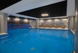 a large swimming pool with chairs in a building at Dedeman Sanliurfa in Urfa