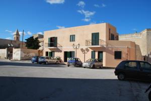 a building with cars parked on the side of a street at Il Giardino Ipogeo in Favignana