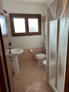 een badkamer met een wastafel, een toilet en een raam bij La corte dell'ulivo in Polazzo