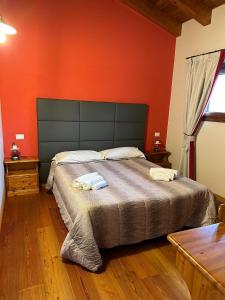 una camera con un grande letto con una parete arancione di La corte dell'ulivo a Polazzo