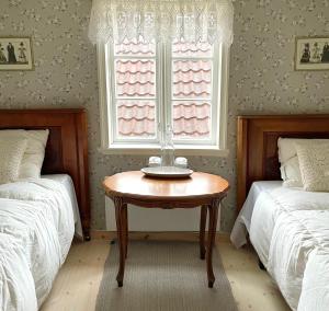 a bedroom with two twin beds and a table in front of a window at Reinertsenhuset in Skudeneshavn