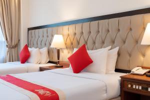 two beds with red pillows in a hotel room at Monoreach Angkor Hotel in Siem Reap