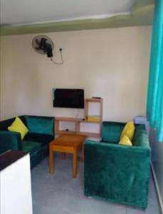 a living room with two green couches and a television at MAGNOLIA SUITES in Ukunda