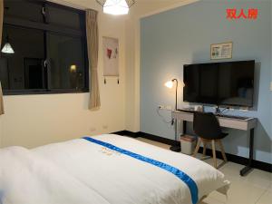 una camera da letto con un letto, una scrivania e una televisione di 塔斯汀精品民宿 a Jinning