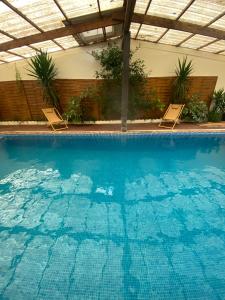 a large swimming pool with two chairs in a building at La Clef du Four in Plesder