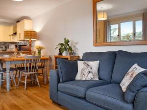 a living room with a blue couch and a kitchen at Willow Wood Cottage 