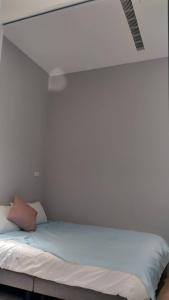 een bed in een kamer met een witte muur bij Rooster B&B in Kaohsiung