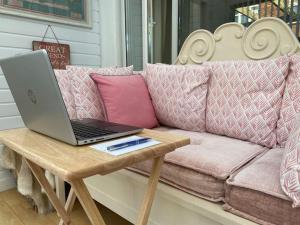 a laptop sitting on a wooden table on a couch at Shoreline hideaway - next to the beach in Holland-on-Sea