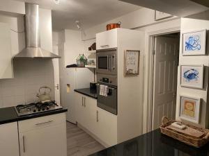 a kitchen with white cabinets and a stove top oven at Shoreline hideaway - next to the beach in Holland-on-Sea