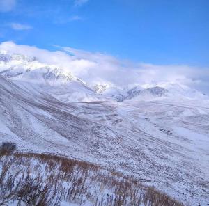una catena montuosa ricoperta di neve con montagne sullo sfondo di Dastan Guest House a Naryn