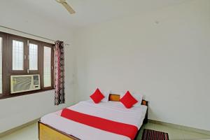 a bedroom with a bed with red pillows and a window at Super OYO Flagship Shivansh Paying Guest House in Varanasi
