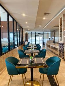 une rangée de tables dans un restaurant avec des chaises bleues dans l'établissement Salatin Hotel Palembang, à Palembang