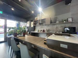 een keuken met een aanrecht met stoelen en een wastafel bij Rooster B&B in Kaohsiung