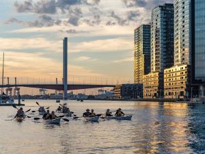 a group of people in boats on a river with buildings at Collins Serviced Apartments in Melbourne