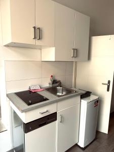 een keuken met witte kasten en een wastafel bij Gemütliches Appartement "Emma" in Halle in Rusches Hof