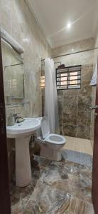 a bathroom with a toilet and a sink and a shower at Résidence Honorine in Pointe-Noire