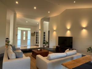 uma sala de estar com 2 sofás brancos e uma televisão de ecrã plano em The Ranch - Coastal Farmhouse midway to Newcastle Airport and Beaches em Salt Ash