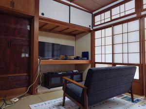 Habitación con silla, escritorio y ventanas. en 39guest house, en Ibusuki