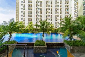 uma piscina com palmeiras em frente a um edifício alto em RedLiving Apartement Cinere Resort By YK rooms Tower Kintamani em Gandul