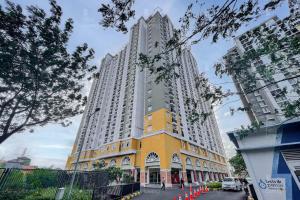 um edifício alto branco e amarelo com cones laranja à volta em RedLiving Apartement Cinere Resort By YK rooms Tower Kintamani em Gandul