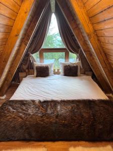 a large bed in a tent with a window at Cabane A-frame CeziAde Tihuta in Piatra Fantanele